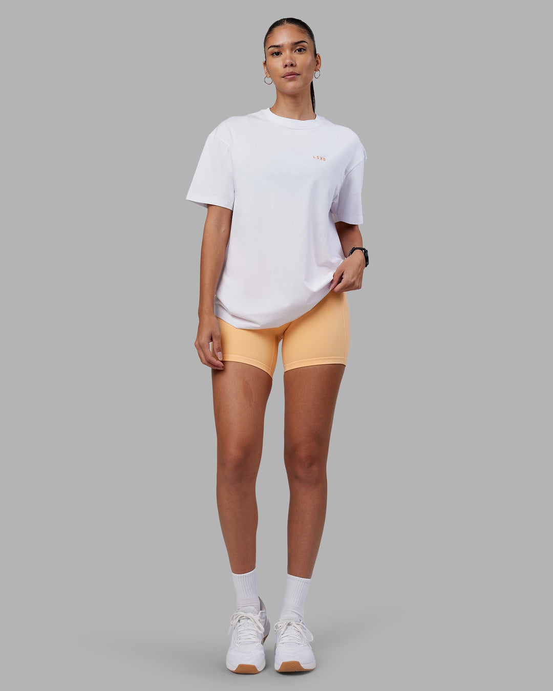 Woman wearing Enjoy the Journey Value Series FLXCotton Tee Oversize - White-Vibrant Orange | Model:Rhiley | Size:XS