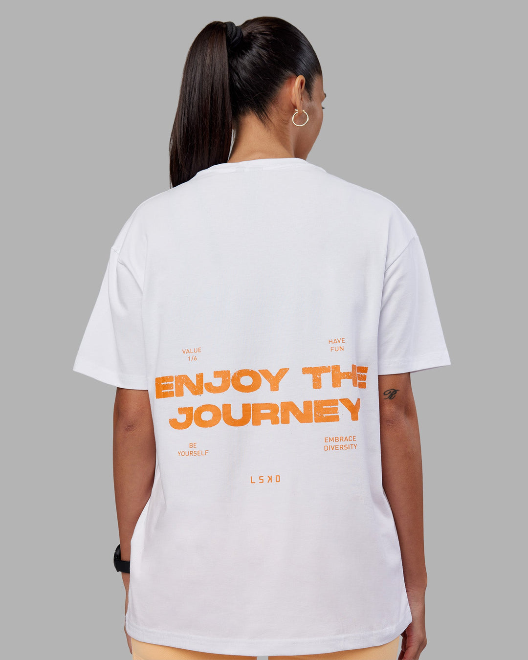 Woman wearing Enjoy the Journey Value Series FLXCotton Tee Oversize - White-Vibrant Orange | Model:Rhiley | Size:XS