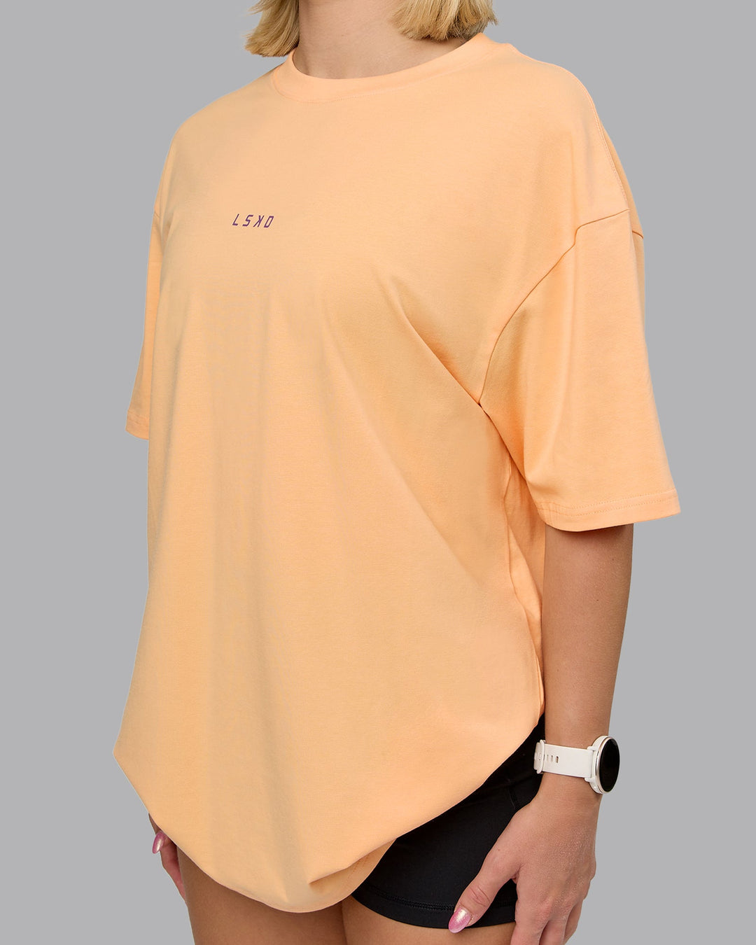 Woman wearing On Repeat FLXCotton Oversized Tee - Peach Fuzz-White | Model:Halle | Size:XS
