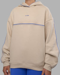 Woman wearing Unisex Oversized Piping Hoodie - Shale Beige-Power Cobalt | Model:Charlize | Size:XS