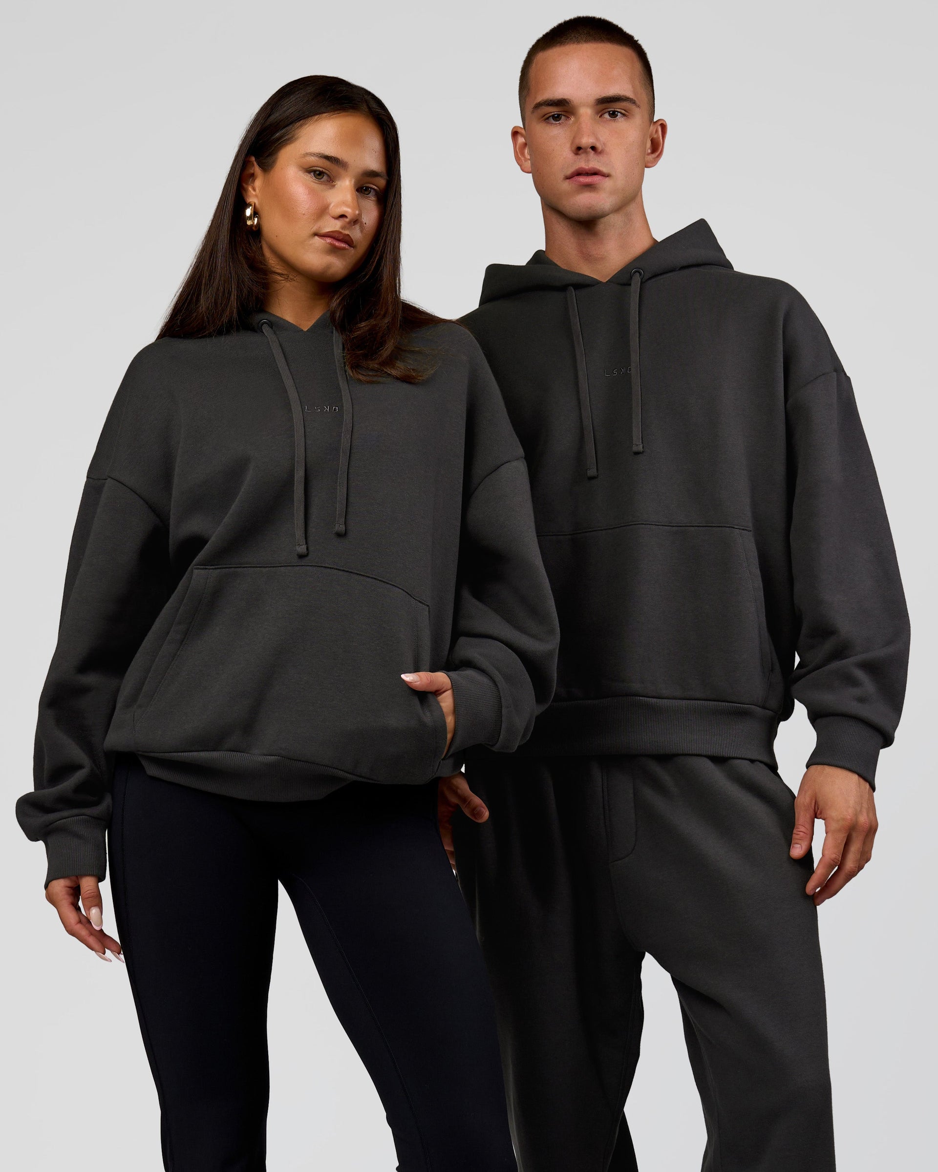 Duo wearing Base Oversized DC Hoodie - Onyx | Model:Albert | Size:M | Model:Bianca | Size:XS