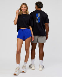 Duo wearing Run Club Elevate FLXCotton Oversized Tee - Black-Electric Indigo | Model:Leilani | Size:XS | Model:Xav | Size:L
