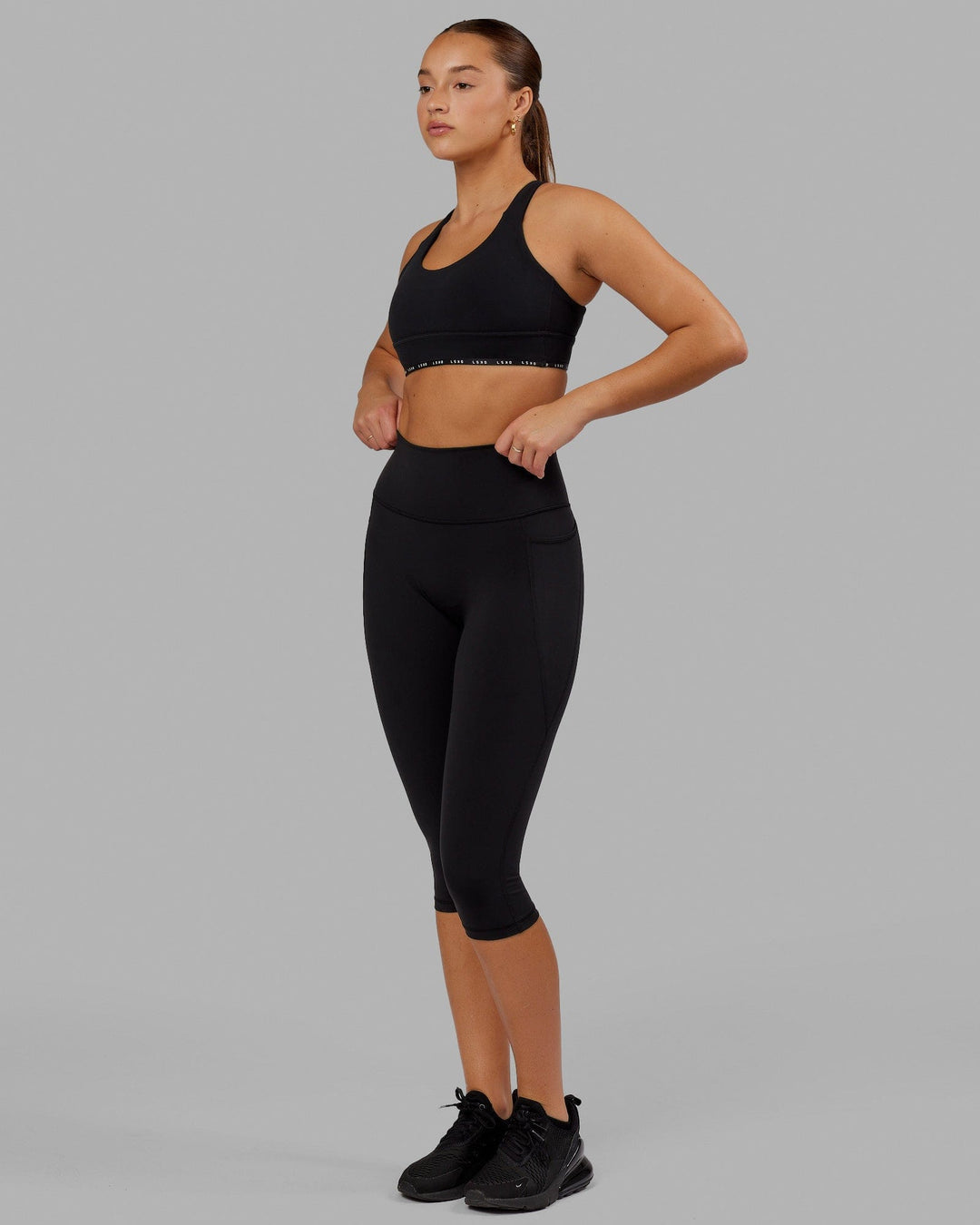 Woman wearing O.G. Fusion Ultra High-Rise 3/4 Legging Pockets - Black | Model:Milly | Size:S