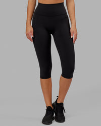 Woman wearing O.G. Fusion Ultra High-Rise 3/4 Legging Pockets - Black | Model:Milly | Size:S