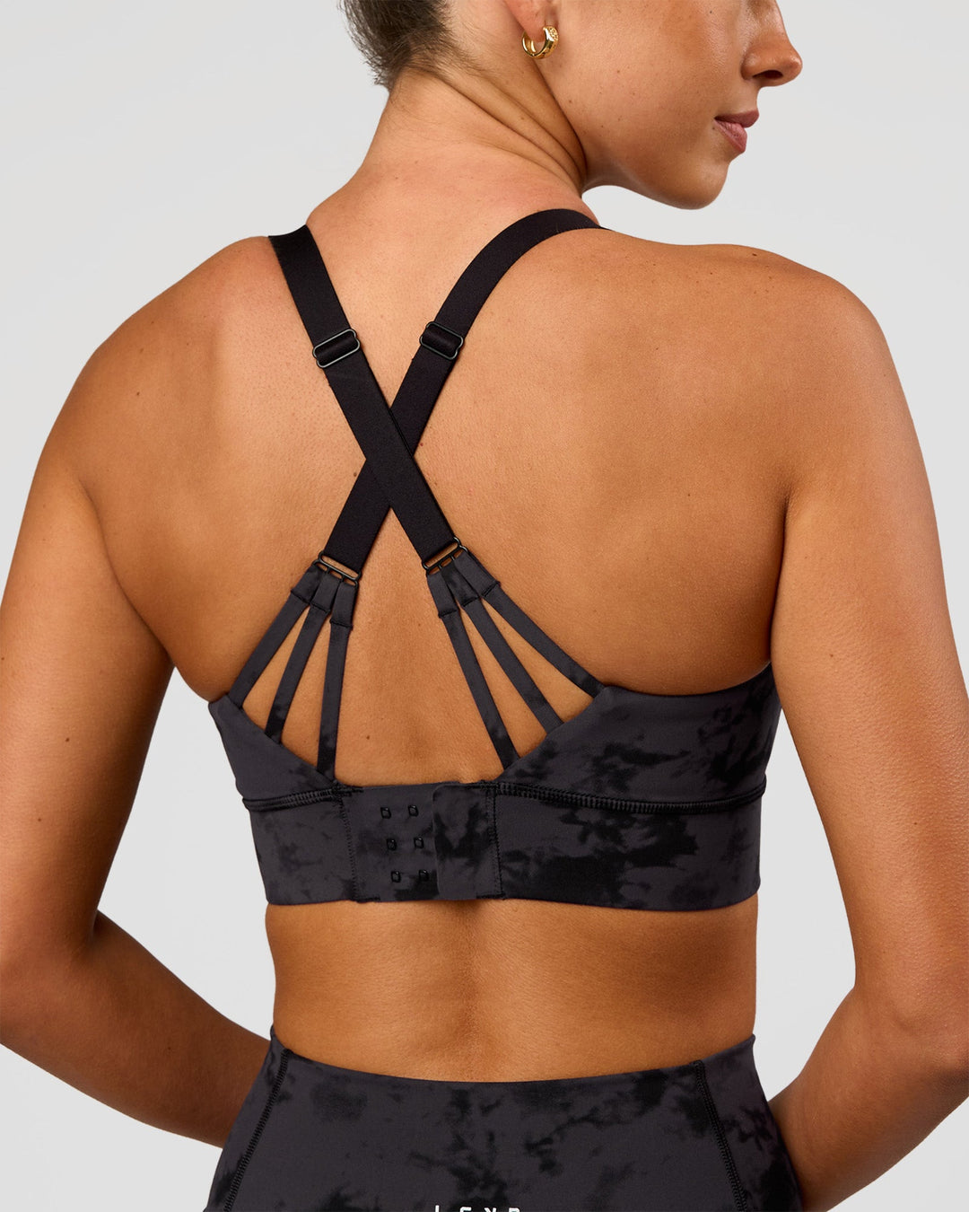 Woman wearing Accelerate Split Strap Sports Bra - Black Tie Dye | Model:Charli | Size:XS - view 1