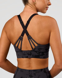 Woman wearing Accelerate Split Strap Sports Bra - Black Tie Dye | Model:Charli | Size:XS | Thumbnail Index: 0