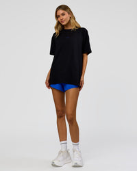 Woman wearing Run Club Elevate FLXCotton Oversized Tee - Black-Electric Indigo | Model:Leilani | Size:XS