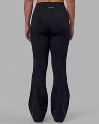 Woman wearing Fusion Ultra High-Rise Flared Petite Legging - Black| Model:Gracie | Size:S