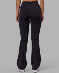 Woman wearing Fusion Ultra High-Rise Flared Legging Pockets - Black | Model:Milly | Size:S